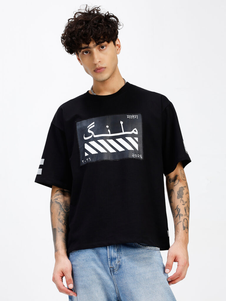 MALANG oversized black T-shirt front view showing Nastaliq calligraphy patch with diagonal stripes and Devanagari script